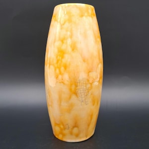 Pode incluir: Um vaso alto de cerâmica com um esmalte marmorizado de cor laranja claro e branco. O vaso tem um fundo ligeiramente arredondado e uma abertura estreita na parte superior.