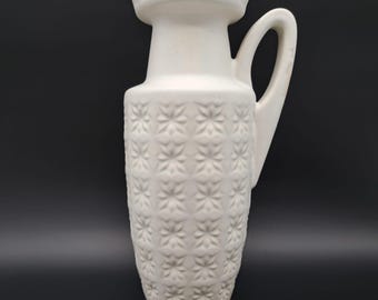 May include: White ceramic vase with a textured, embossed pattern of stars. The vase has a wide mouth and a single handle.
