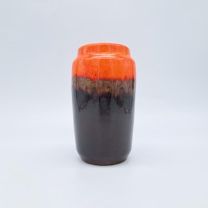 Puede incluir: Un jarrón de cerámica cilíndrico con acabado brillante. La parte superior es de color naranja brillante, seguida de una banda marrón y una base marrón oscuro. Este jarrón decorativo es adecuado para la decoración del hogar y mide unos 20 cm de altura.