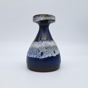 May include: A ceramic vase with a flared rim and a tapered neck, featuring a deep blue base that transitions into a speckled white and light blue glaze around the midsection, finished with a dark brown tone at the bottom and the rim edge.