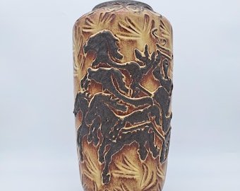 Peut inclure: Un vase cylindrique en céramique avec une surface texturée. Le vase présente un motif en relief de personnages et de feuillage dans des tons de brun et de beige. Le vase a un bord et une base brun foncé.