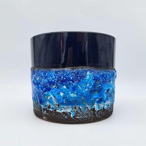 Peut inclure: Un pot en céramique bleu et brun avec un glaçage texturé. Le pot a un dessus bleu foncé et un glaçage bleu et blanc sur le fond.
