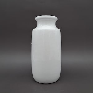 Puede incluir: Un jarrón de cerámica blanco con cuerpo redondeado y cuello acampanado. El jarrón tiene un acabado brillante y está sobre un fondo gris oscuro. El jarrón es un objeto decorativo.