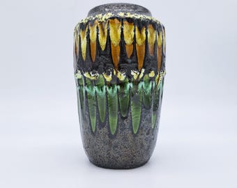 May include: A cylindrical ceramic vase featuring a textured dark gray base with a prominent drip glaze pattern. The upper section displays vertical streaks of yellow and brown, while the lower section features green drips over the dark gray surface.