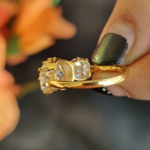 Puede incluir: Un anillo de oro con tres piedras preciosas transparentes. El anillo est&aacute; engastado con una piedra central grande y dos piedras m&aacute;s peque&ntilde;as a cada lado.