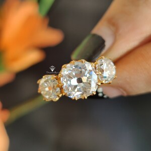 Puede incluir: Un anillo de oro con tres diamantes grandes, claros y de corte cuadrado. Los diamantes est&aacute;n engastados en garras y tienen un acabado pulido.