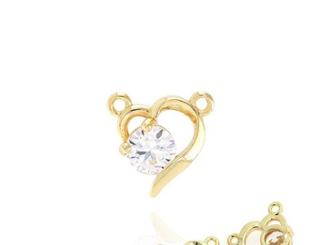 Puede incluir: Tres dijes de joyería dorados en forma de corazón. Cada dije presenta una gema redonda y transparente engastada en el diseño del corazón. Los dijes tienen pequeños bucles para sujetarlos a otras joyas.