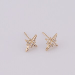 May include: A pair of gold star-shaped earrings with clear cubic zirconia stones.