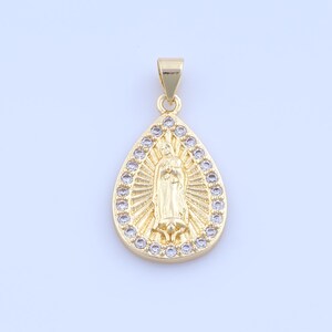 May include: Gold-colored pendant in a teardrop shape, featuring a religious figure in the center. The pendant is surrounded by small, clear crystals. The bail is also gold-colored.