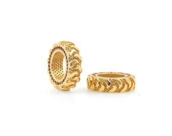 May include: Two gold-colored tire-shaped beads with a black inner rim. The beads are made of metal and have a textured surface.