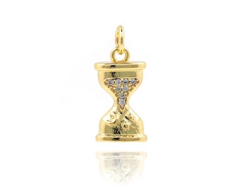 May include: Gold-toned hourglass charm with clear crystal accents. The charm is designed to be added to a necklace or bracelet.