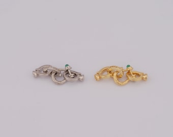 May include: Two silver and gold chain links with green gemstone accents. The links are connected together and are a decorative element for a necklace or bracelet.