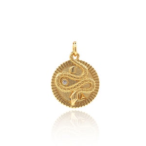 May include: Gold pendant necklace featuring a snake design with a small clear stone in the center. The snake is coiled around a circular pendant with a textured edge.