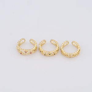 May include: Three gold rings with a star design and small red, green, and blue gemstones. The rings are open and can be adjusted to fit different finger sizes.