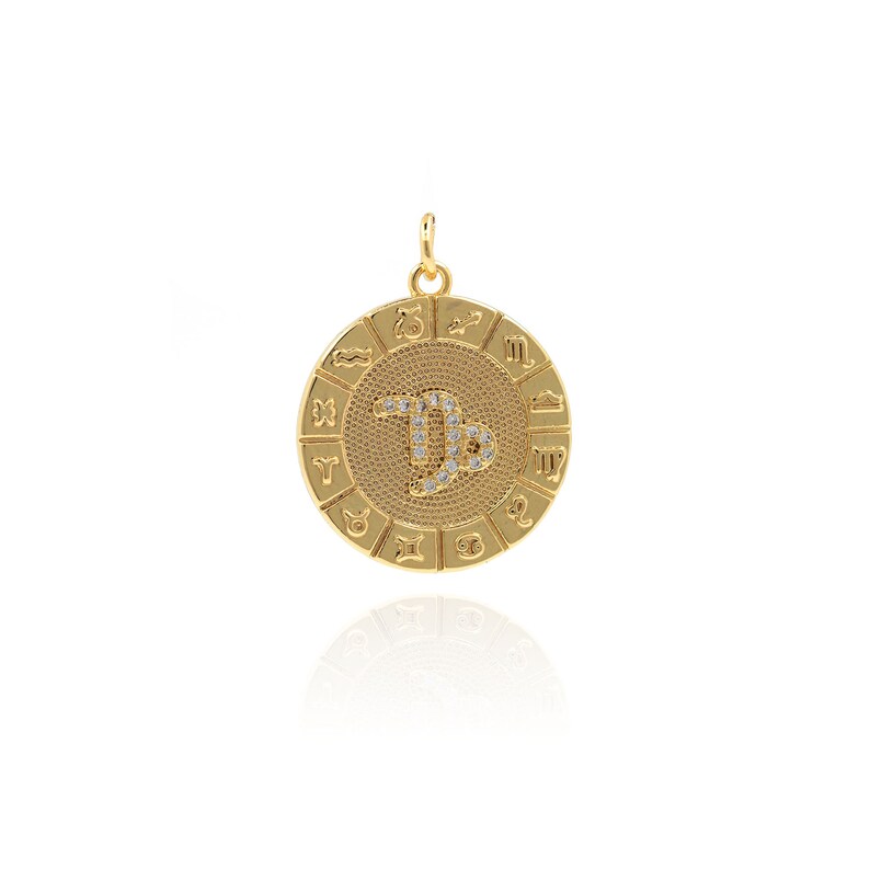 May include: Gold-toned zodiac pendant featuring a Capricorn symbol with clear rhinestones. The pendant is round and has all 12 zodiac signs around the edge.