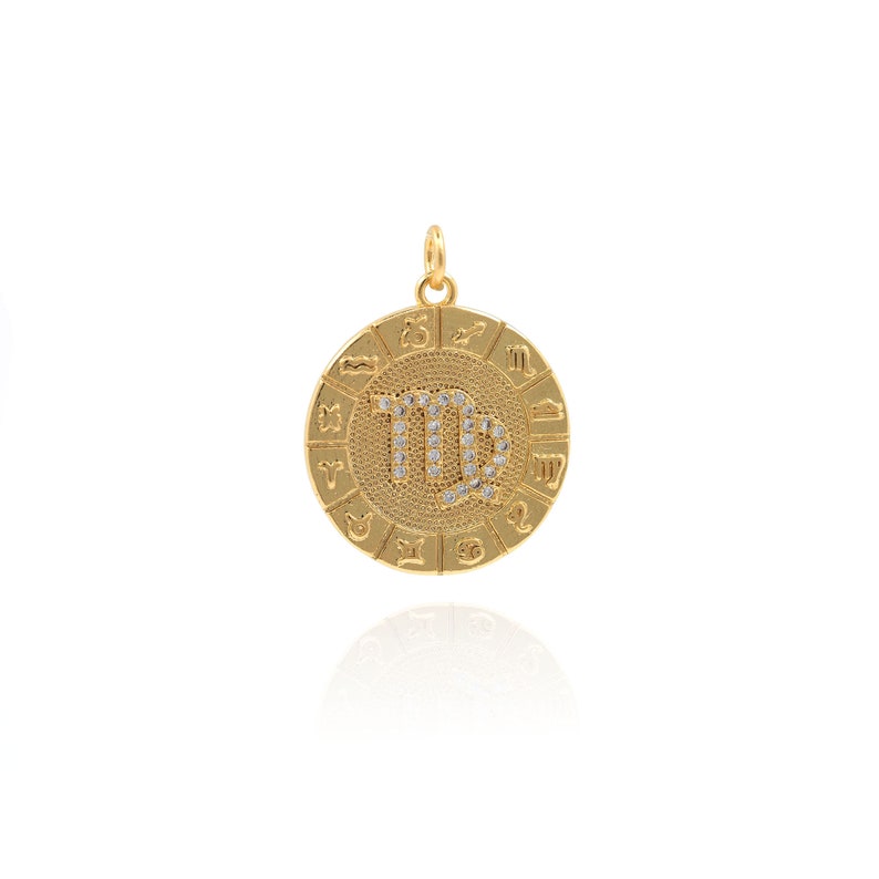 May include: Gold-toned zodiac pendant featuring the Virgo constellation with clear rhinestones. The pendant is round and has a textured surface. The outer edge of the pendant features the zodiac symbols for each sign.