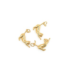 May include: Three gold-colored cat charms with a loop for attaching to a necklace or bracelet.