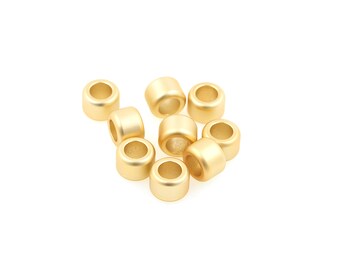 Könnte beinhalten: Eine Gruppe von zehn goldfarbenen Metallperlen, verstreut auf weißem Hintergrund. Die Perlen sind rund und haben eine glatte, glänzende Oberfläche.