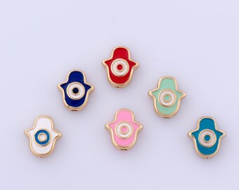 Puede incluir: Una colección de amuletos de mano de Hamsa coloridos. Cada amuleto presenta un contorno dorado con un diseño de ojo central. Los amuletos son de varios colores, incluyendo azul, rojo, rosa, verde y blanco, con un borde dorado.