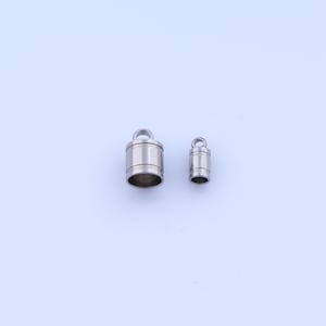 May include: Two small, silver-colored metal objects with a cylindrical shape and a loop at the top. The larger one has a wider base and a hollow interior. The smaller one is a miniature version of the larger one.