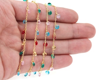 May include: A gold chain necklace with colorful beads hanging from it. The beads are in shades of pink, blue, green, and red.