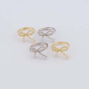 May include: Four adjustable rings with a bow design and pearl accents. Two rings are gold, and two rings are silver.
