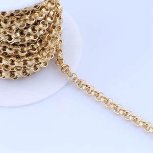 Könnte beinhalten: Eine Rolle goldfarbener Kette mit einem strukturierten, abgerundeten Kettenglied-Design. Die Kette ist teilweise abgewickelt und zeigt das komplizierte Muster der Glieder. Geeignet für Schmuckherstellung oder Bastelprojekte.