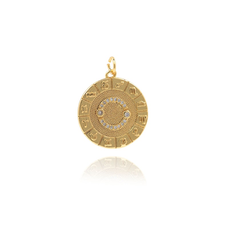 May include: Gold-toned zodiac pendant with a circle of clear rhinestones around the edge. The pendant features the twelve zodiac signs in a circle around the edge.