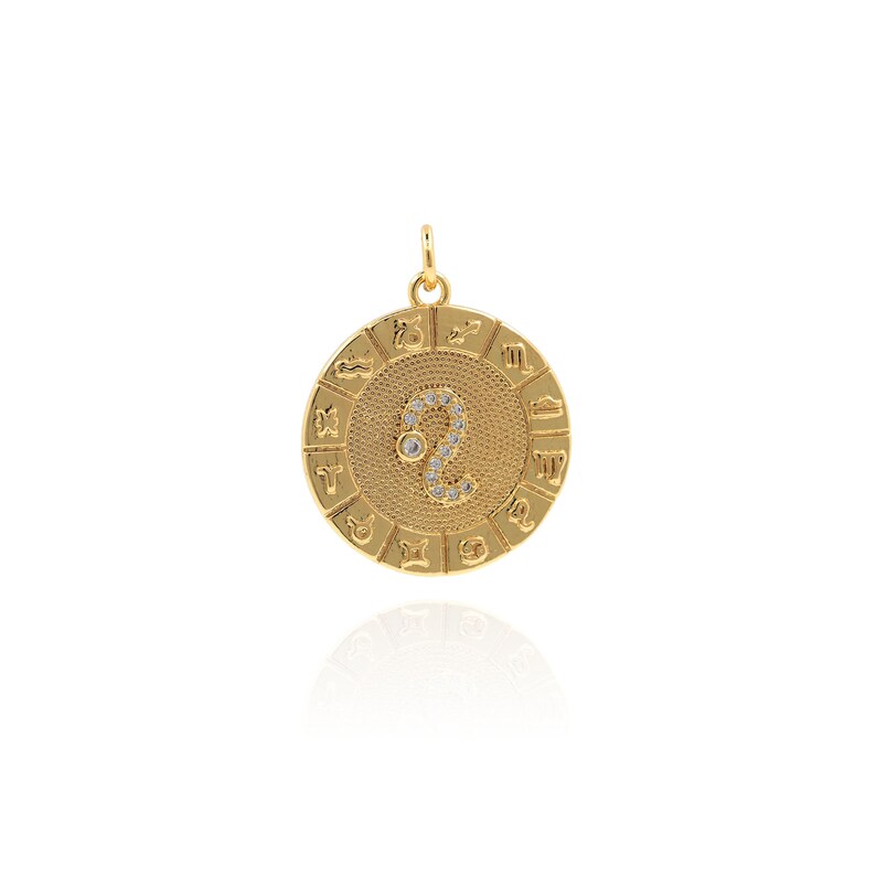 May include: Gold zodiac pendant featuring a Leo symbol with clear rhinestones. The pendant is round and has all 12 zodiac signs around the edge.