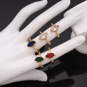 Peut inclure: Cinq bagues en or avec des pierres précieuses en forme de marquise. Les bagues présentent des pierres précieuses claires, roses, bleues, vertes et rouges.