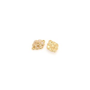 May include: Two gold-tone flower-shaped charms with white enamel centers. Each charm has three loops for attaching to jewelry.