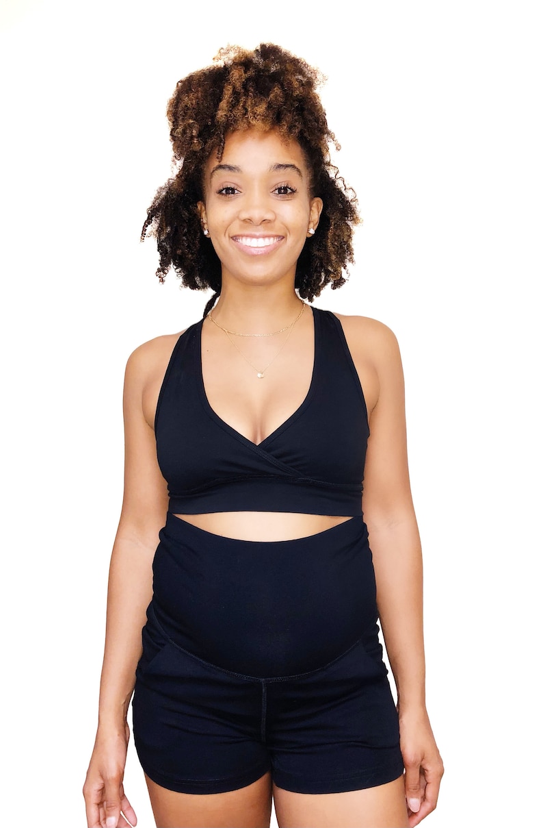 Puede incluir: Una mujer con un sujetador deportivo negro y pantalones cortos negros. Los pantalones cortos tienen cintura alta y est&aacute;n dise&ntilde;ados para ropa de maternidad.