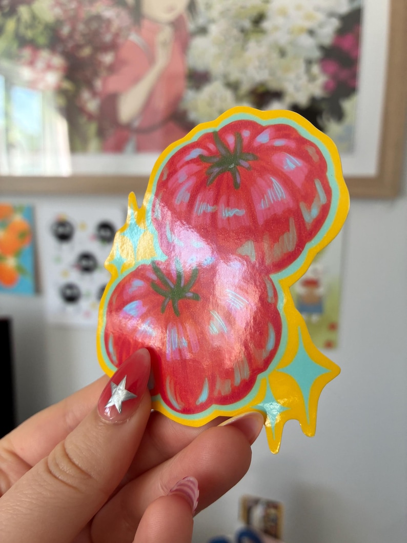 K&ouml;nnte beinhalten: Ein farbenfroher Aufkleber mit zwei roten Tomaten mit gr&uuml;nen Stielen. Der Aufkleber hat einen gelben Rand mit blauen und gelben Sternen-Akzenten. Die Tomaten haben ein gl&auml;nzendes, schillerndes Finish.
