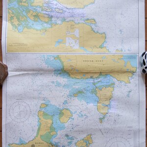 May include: A vintage nautical chart depicting the Loch Boisdale, South Uist, and Sound of Barra regions. The map uses blue, yellow, and white colors, with depth measurements in metres. The chart is folded and has text in English.