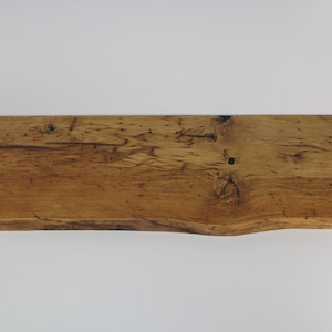 May include: A rustic wooden shelf made from reclaimed wood with a natural finish. The shelf has a live edge and a slightly uneven surface.