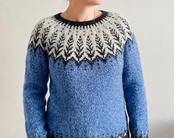 May include: A long-sleeved knit sweater featuring a blue body and a round neckline. The yoke displays a white and dark gray geometric pattern resembling pine trees. The cuffs and bottom hem are finished with a dark gray ribbed knit border.