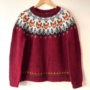 Handknit Icelandic wool sweater with fox pattern yoke in garnet red, fluffy texture of natural Icelandic wool – handmade Nordic lopapeysa sweater. Fox Icelandic sweater wool lopapeysa handmade Nordic animal design, Red Hand-knitted Icelandic wool Into the Wild sweater with a fox yoke pattern, made from genuine Icelandic wool