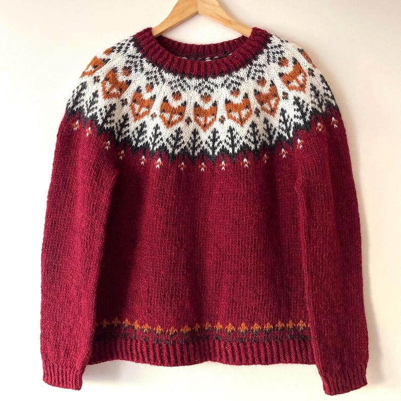 Handknit Icelandic wool sweater with fox pattern yoke in garnet red, fluffy texture of natural Icelandic wool – handmade Nordic lopapeysa sweater. Fox Icelandic sweater wool lopapeysa handmade Nordic animal design, Red Hand-knitted Icelandic wool Into the Wild sweater with a fox yoke pattern, made from genuine Icelandic wool