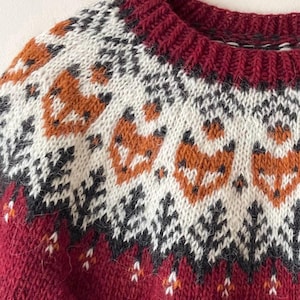 Close-up of a red hand-knitted Icelandic wool sweater with apricot fox yoke