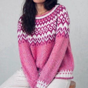 Op de afbeelding: Een gebreide trui met lange mouwen en een levendig roze en wit Fair Isle-patroon op het schouderstuk en de zoom. De trui heeft een verloop-effect, van diep magenta aan de bovenkant naar een lichtere, gespikkelde roze kleur onderaan.