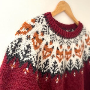 Red hand-knitted Icelandic wool fox sweater displayed on a hanger