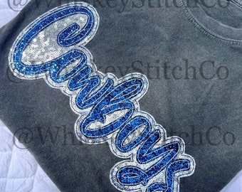 May include: A gray t-shirt with a blue and silver sequined "Cowboys" design. The shirt has a distressed look and is perfect for showing your team spirit.