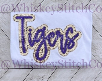 May include: White t-shirt with a gold and purple sequined "Tigers" design.