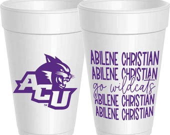 Może przedstawiać: Dwa białe kubki z pianki. Jeden kubek ma fioletowe logo dzikiego kota i litery ACU. Drugi kubek ma fioletowy tekst z napisami "Abilene Christian" i "go wildcats". Kubki są przeznaczone na napoje.