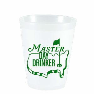 May include: A white plastic cup with a green graphic that reads "Master Day Drinker." The graphic includes a golf flag and a stylized outline of a golf course. The cup is designed for beverages.