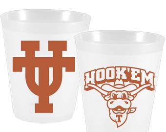 May include: Two white plastic cups with orange logos. The first cup has a large orange "UT" logo. The second cup has an orange logo that says "HOOK'EM" with a cartoon mascot of a Longhorn steer wearing a cowboy hat.