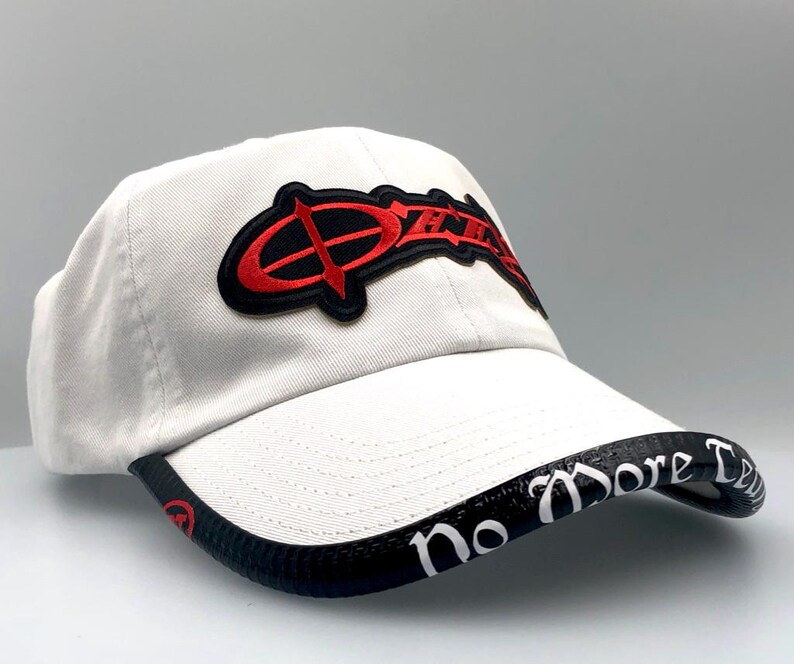 May include: A white baseball cap with a curved brim. The cap features a red and black logo on the front and the words "No More Tears" in white on the brim. The cap is made of a soft material.