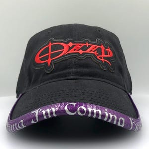 May include: Black baseball cap with a red "Ozzy" logo on the front. The brim is purple with the text "I'm Coming Home" in white. The cap is made of a durable fabric.