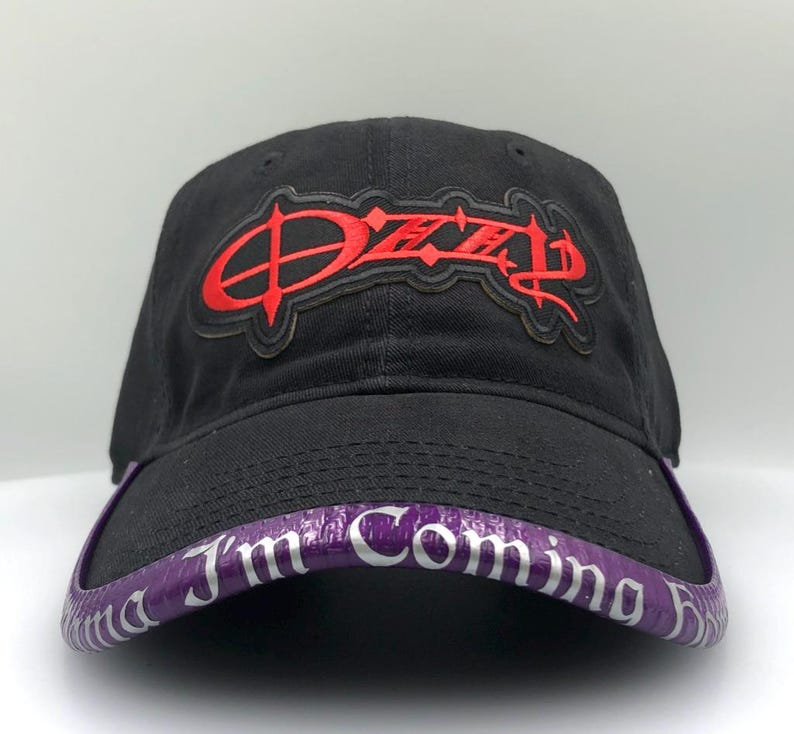 May include: Black baseball cap with a red "Ozzy" logo on the front. The brim is purple with the text "I'm Coming Home" in white. The cap is made of a durable fabric.