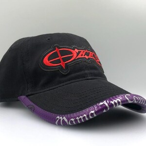 May include: Black baseball cap with a curved brim. The cap features a red logo on the front and a purple brim with white text. The cap is made of a soft material and has a curved brim.